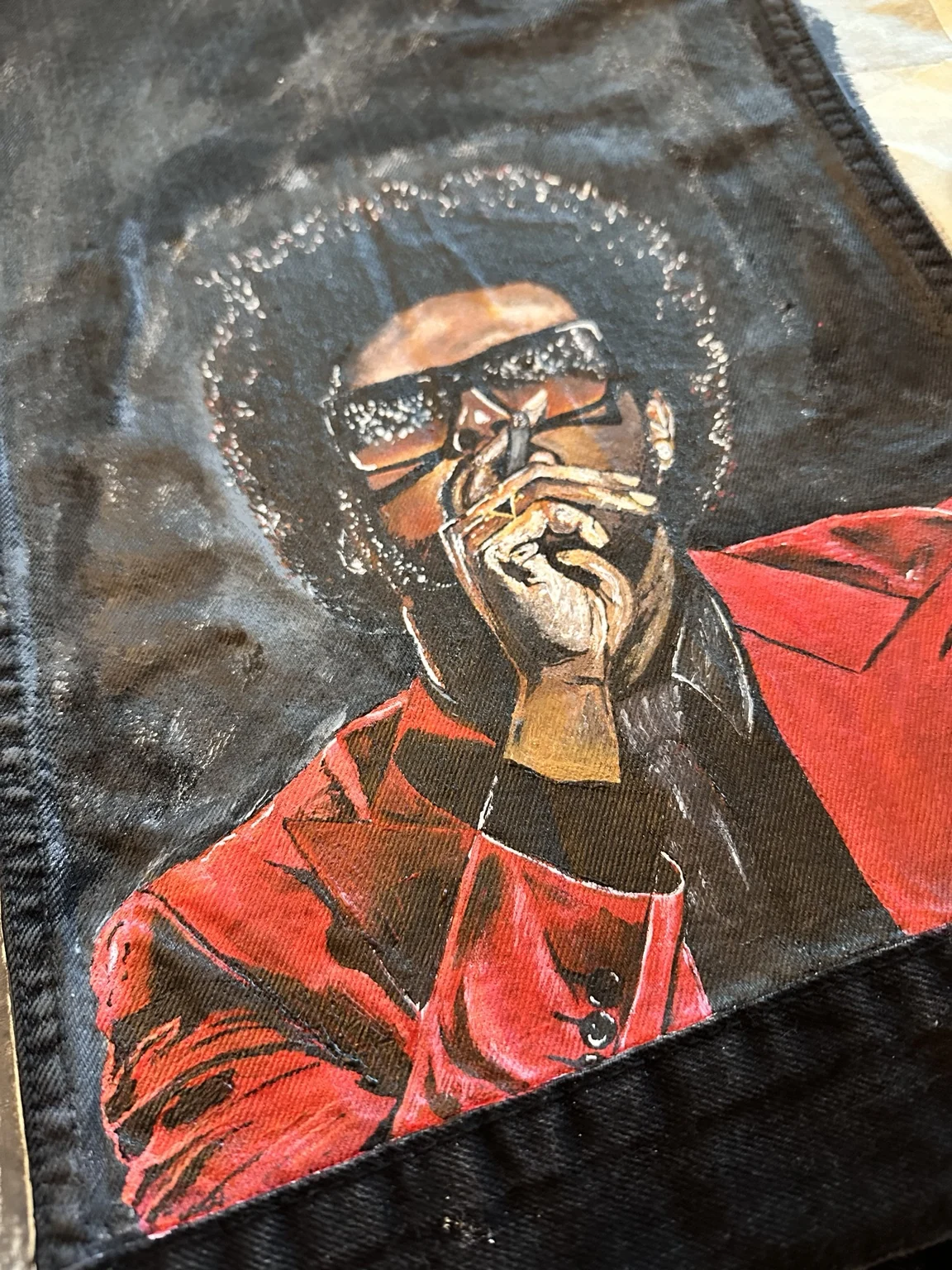Close-up of Dem’s hand-painted portrait work on black denim